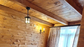 A cozy room with wooden walls and ceiling, a purple sofa, a wooden coffee table, and a window with curtains. - Zenith Campsite Apartments (Niksic)