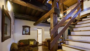 Um interior rústico com escada de madeira, um sofá e um quadro na parede.