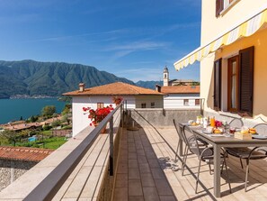 A terrace with a table set for breakfast overlooking a lake and mountains. - Lovely apartment for 4 people with A/C, WIFI, TV and patio (Mezzegra)