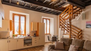 Una cocina moderna con armarios de madera, horno empotrado y comedor con una escalera de madera.