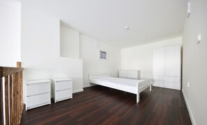 A bedroom with a single bed, two bedside tables, a wardrobe, and a small framed picture on the wall.