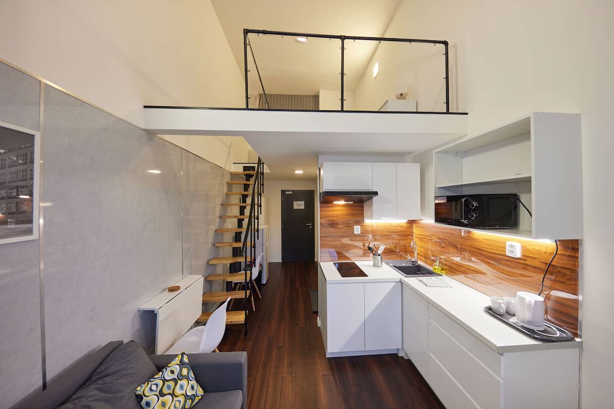 Eine kompakte Wohnung mit Küchenzeile, Essbereich und Wohnraum mit Sofa sowie einer Treppe, die in ein Obergeschoss führt.