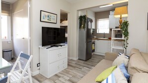 A compact living space with a kitchenette, a flat-screen TV, a sofa with cushions, and a dining area with a table and chairs. - Cosy apartment for 4 guests with A/C, WIFI, TV and terrace (Tossa De Mar)