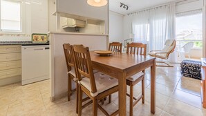 Una cocina moderna con armarios blancos, una mesa de comedor de madera y una lámpara colgante.