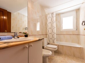 A bathroom with a sink, mirror, toilet, and bathtub.