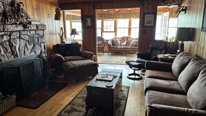 A cozy cabin interior with a stone fireplace, leather sofas, and a rustic wooden interior. - Make memories at this Big Chetac Lake Cottage (Birchwood)