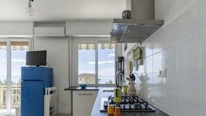 A modern kitchen with a gas stove, a blue refrigerator, and a view of the sea through large windows. - Nice apartment for 4 guests with A/C, WIFI and balcony (Sanremo)
