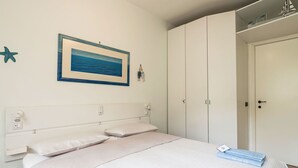 Ein Schlafzimmer mit einem Bett, einem Kleiderschrank, einem gerahmten Bild und einer Meerstern-Dekoration.
