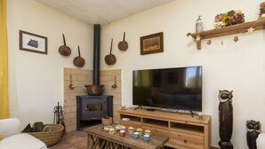 Un salon chaleureux avec une cheminée, un téléviseur à écran plat et une table basse en bois.