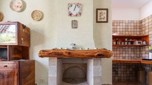 A stone fireplace with a wooden mantel, surrounded by kitchen shelves and a rustic wooden cabinet.