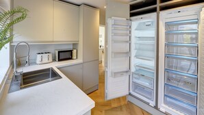 Une cuisine moderne dotée d’appareils électroménagers intégrés, d’un évier en acier inoxydable et d’un four à micro-ondes.