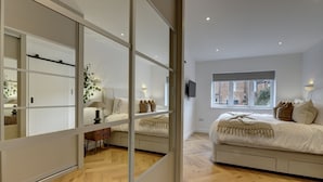 Une chambre à coucher moderne avec un grand lit, un miroir et une fenêtre.