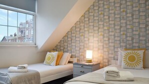Ein Schlafzimmer mit zwei Betten, einem Fenster und einer Wand mit Muster.