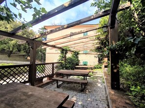 Relax in the shaded patio area, surrounded by lush greenery and comfortable seating.