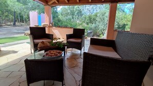 Ein überdachter Patio-Bereich mit Korbmöbeln und einem Tisch mit Gebäck.