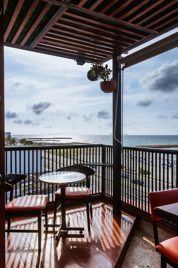 A covered outdoor seating area with a view of the ocean.