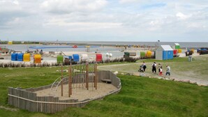 A beachside playground with a wooden play structure, a sandy area, and a grassy field. - Cosy apartment for 6 guests with WIFI, TV and terrace (Bremerhaven)