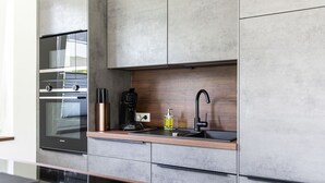 A modern kitchen with a built-in oven, a coffee maker, and a sink.