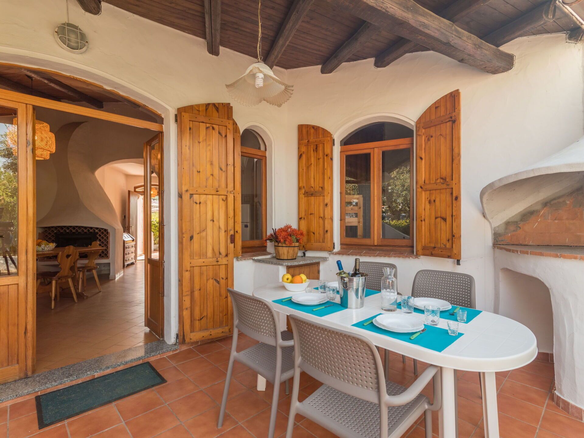 A dining area with a table set for four, wooden shutters, a fireplace, and a view of the outdoors.