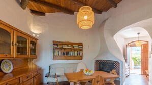 Una cocina acogedora con armarios de madera, una mesa de comedor, sillas, una estantería y una chimenea.