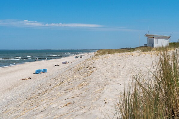 A beach with a lifeguard tower, sandy dunes, and the ocean.