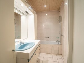 A modern bathroom with a sink, mirror, and shower.