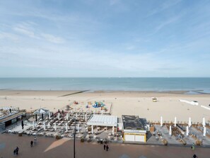 A beachside hotel with outdoor seating, a lifeguard tower, and a view of the sea.