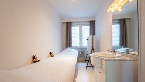 A modern bathroom with a large bathtub, a vanity with a mirror, and a radiator.