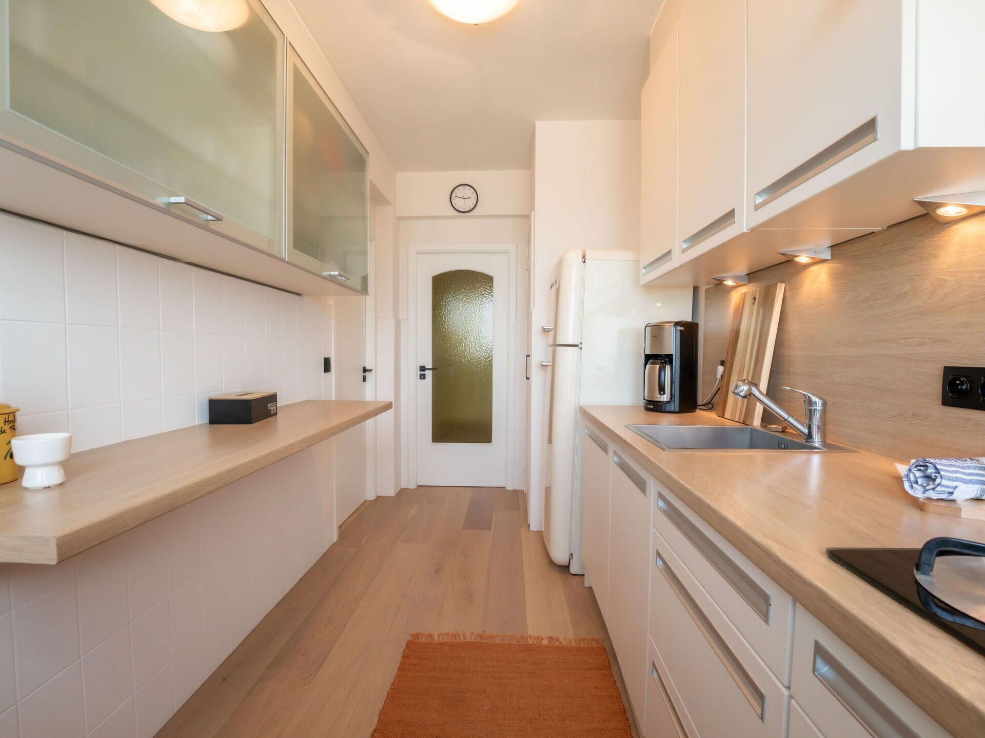 A modern kitchen with a wooden countertop, stainless steel sink, and a coffee maker.