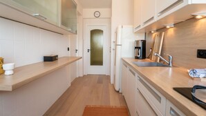 A modern kitchen with a wooden countertop, stainless steel sink, and a coffee maker.
