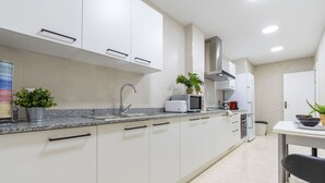 Una cocina moderna con armarios blancos, encimera de granito, pileta de acero inoxidable y microondas.