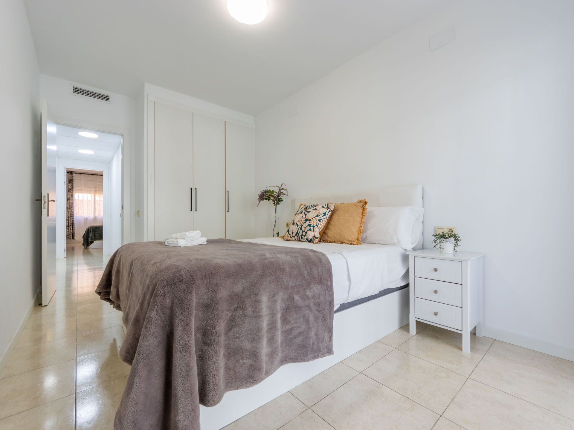 Une chambre à coucher comprenant un lit, une table de chevet, une commode et une porte donnant sur une autre pièce.