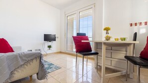 A modern bedroom with a bed, a TV, a desk, and a chair.