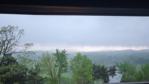 Blick von einem Balkon auf eine bewaldete Landschaft mit einer Sitzgruppe und Lichterketten.