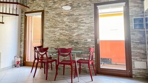 A dining area with a stone wall, a glass table, and red chairs. - Beautiful apartment for 2 guests with WIFI, TV and balcony (Florence)