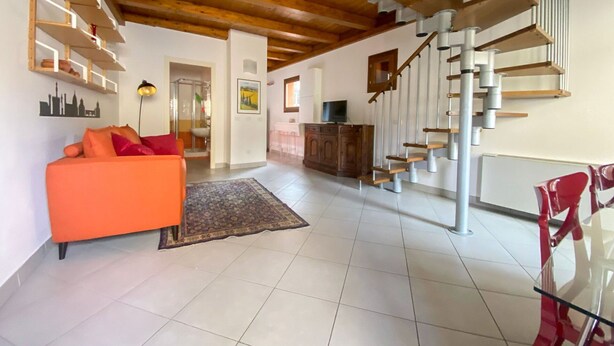 A spacious living area with a modern staircase, a sofa, and a dining area. - Beautiful apartment for 2 guests with WIFI, TV and balcony (Florence)