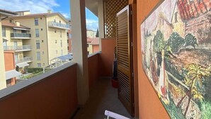 A balcony with a view of neighboring buildings, a painting on the wall, and a white table with a power strip. - Beautiful apartment for 2 guests with WIFI, TV and balcony (Florence)