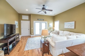 A living room with a TV, sofa, lamp, and ceiling fan.
