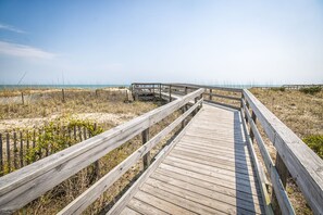 A wooden boardwalk leading to a beach with a wooden structure at the end.