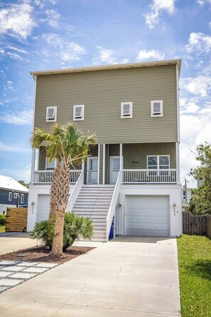 A two-story building with a front porch, a garage, and a palm tree.