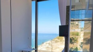 A modern bedroom with a large window offering a view of the sea. - Nili Deluxe (Sarandë)