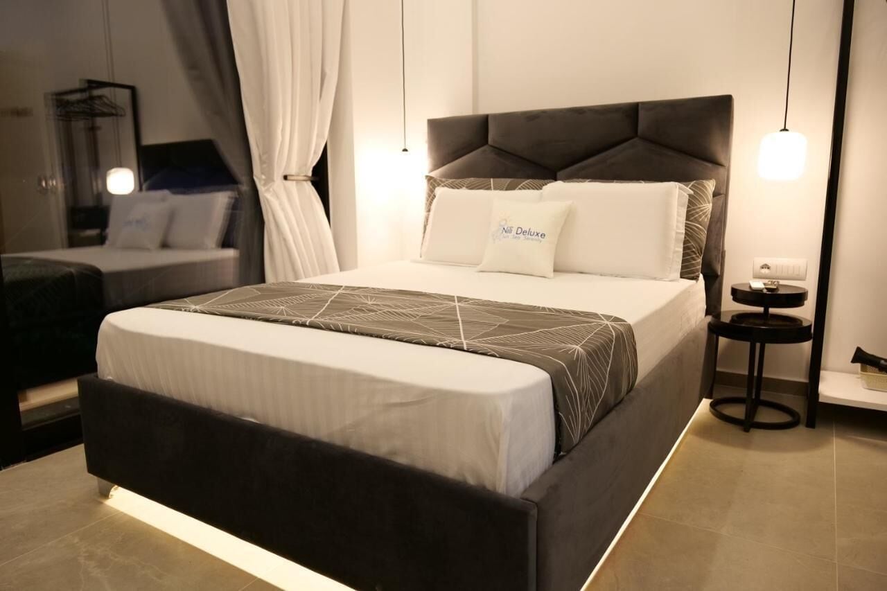 A modern hotel room with a large bed, a bedside table, and a nightstand.