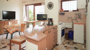 A kitchen with a wooden counter, a television, a microwave, a coffee maker, and a sink.