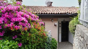 A building with a tiled roof, a stone wall, and a door with a small statue.