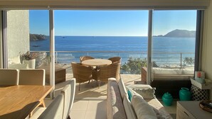 Een balkon met uitzicht op zee, rieten meubels en een tafel.