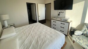 Een hotelkamer met een bed, een dressoir, een televisie en een stoel.