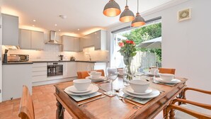A modern kitchen with white cabinets, a dining table set for four, and a view of the outdoors.
