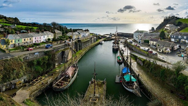 A coastal town with a narrow waterway, historic buildings, and a small dock with boats.