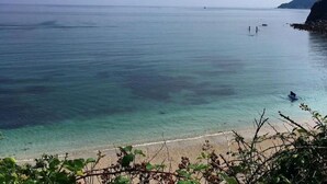 A beach with clear water and a rocky coastline.