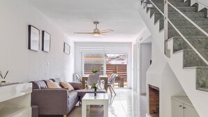 Una sala moderna con sofá, mesa de centro y una escalera que sube a un piso superior.